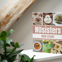 Image of the NUsisters New Start Cookbook. An 8 week guide for a health overhaul. The book is sitting on a table with wood and a plant in the background.