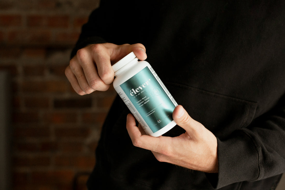 A mans hands holding a bottle of Elever Plus MensBalance. Boost. Digestion. Energy. Renew. Refresh. 60 capsules. 