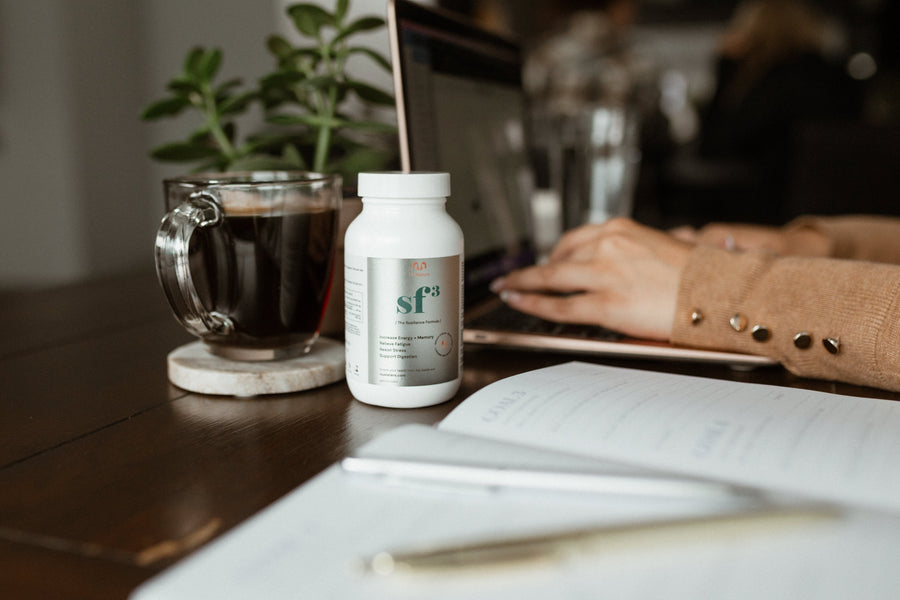 NUsisters. SF3. Stress Free Three 3. Increased energy + memory. Relieve Fatigue. Resist Stress Support Digestion. 60 capsules. In the background a laptop and a woman on it and a coffee.